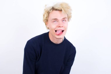young blond man  showing grimace face crossing eyes and showing tongue. Being funny and crazy clipart
