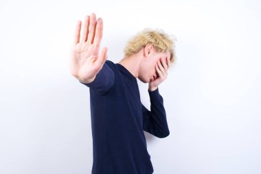 Genç sarışın adam avuçlarıyla gözlerini kapatıyor ve herkesten saklanmaya çalışıyor..