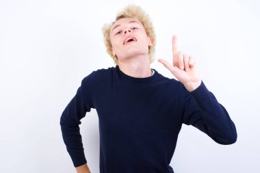 Genç sarışın adam parmağını kaldırıyor. Fikri var ve poz veriyor.