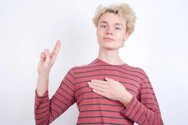 Young Blond Man Smiling Swearing Hand Chest Fingers Making Loyalty — Φωτογραφία Αρχείου