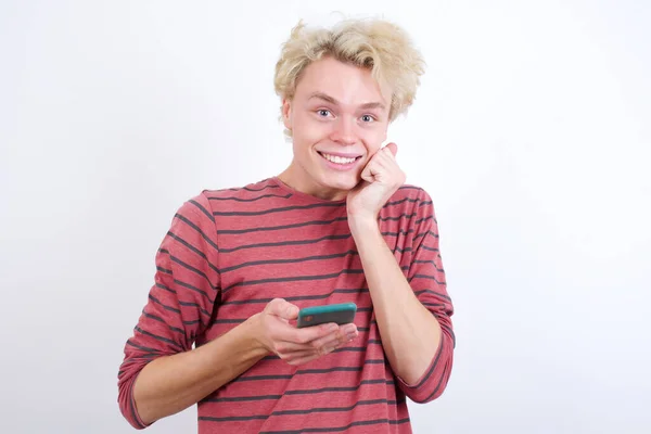 Joyous Jonge Blonde Man Poseert Met Mobiele Telefoon Apparaat Typt — Stockfoto