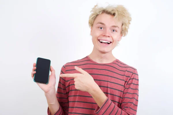 魅力的な陽気な若いブロンドの男の手の携帯電話を保持し 黒画面を示す — ストック写真