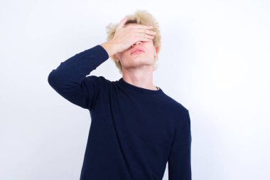 Kafkasyalı genç bir adam, şaşırtmak için elleri yüzlerinde, gülüyor ve gülümsüyor. Kör kavram.