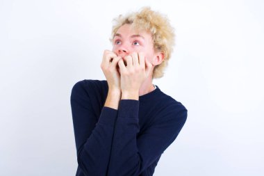 Korkak genç beyaz adam ellerini ağzının kenarında tutuyor, korkmuş ve korkmuş hissediyor, fobisi, şoku ve korkmuş bir konsepti var..