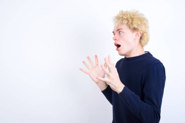 Genç beyaz adam yüksek sesle bağırıyor, gözleri açık ve elleri gergin tutuyor..