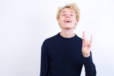 Kafkasyalı genç bir adam kaya hareketi yapıyor ve kameraya gülümsüyor. En sevdiği konsere gitmeye hazır..