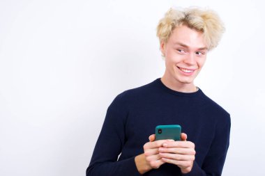 Genç beyaz adam el ele tutuşuyor ve yeni cep telefonunu gösteriyor.