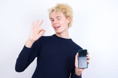 Kafkasyalı genç bir adam hücresinde el ele tutuşmuş, tamam işareti gösteriyor.