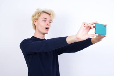 Genç beyaz bir adam sosyal medyaya göndermek için selfie çekiyor ya da arkadaşlarıyla görüntülü görüşme yapıyor..