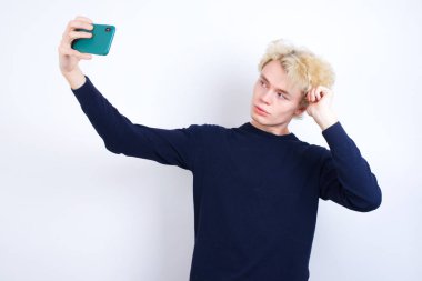 Genç beyaz adam gülümsüyor ve kendi fotoğrafını sosyal medyaya yüklemeye hazır..