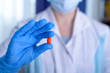 Renkli haplarla dolu eldivenli eller, elinde haplar tutan tıp görevlisinin eli.