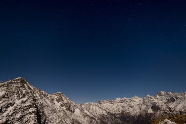 Ay ışığı altında kış Alpler'de yukarıda yıldızlı gökyüzü