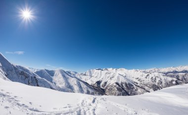 Sun star glowing over snowcapped mountain range, italian Alps clipart