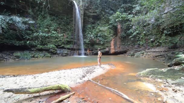Woman looking at a stunning multicolored natural pool with scenic waterfall in the rainforest of Lambir Hills National Park, Borneo, Malaysia. — Stock Video