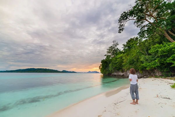 Turist uzak Togean Adaları, Orta Sulawesi, Endonezya, son yıllarda büyüyen seyahat hedef plajda oturan rahatlatıcı bir günbatımı izliyor. — Stok fotoğraf