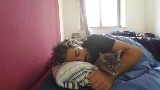 Uyuyan adamla yatakta yatan evcil kedi. — Stok video