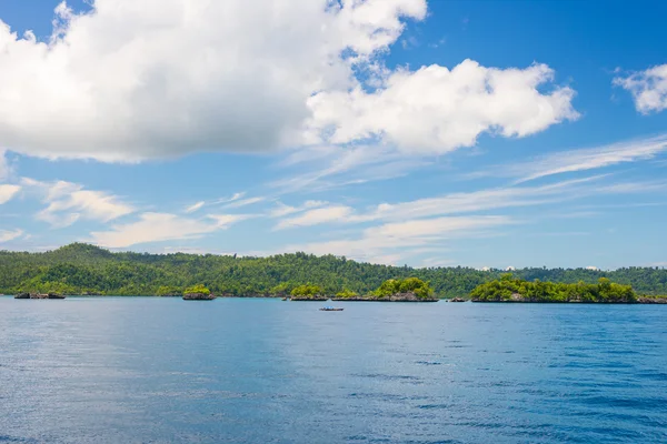 Costa rocosa de la isla manchada por islotes y cubierta por una densa selva verde en el colorido mar de las remotas islas Togean (o islas Togian), Sulawesi Central, Indonesia . —  Fotos de Stock