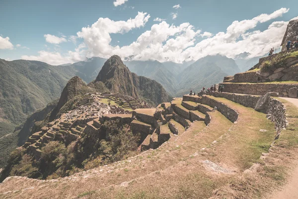 Machu Picchu arkeologiska platsen, vidvinkel vy från terrasserna ovan med vacker himmel. Tonad bild. — Stockfoto