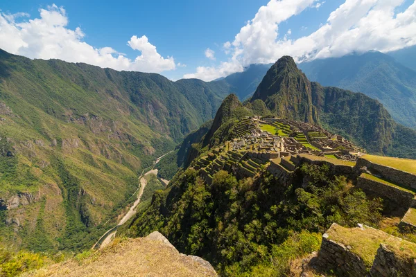 Machu Picchu archäologische Stätte beleuchtet durch das Sonnenlicht. Weitwinkelblick von den Terrassen oben mit malerischem dramatischen Himmel. — Stockfoto