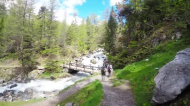 Yemyeşil yeşil vadide vahşi akışıyla hiking backpackers. Yaz macera ve keşif İtalyan Fransız Alpleri üzerinde.