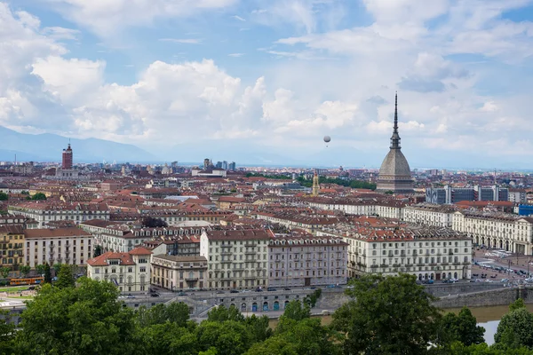 Cityscape of Torino (Turin, Italy) with the Mole Antonelliana and the hot-air baloon towering over the buildings. Wind storm clouds over the Alps in the background.