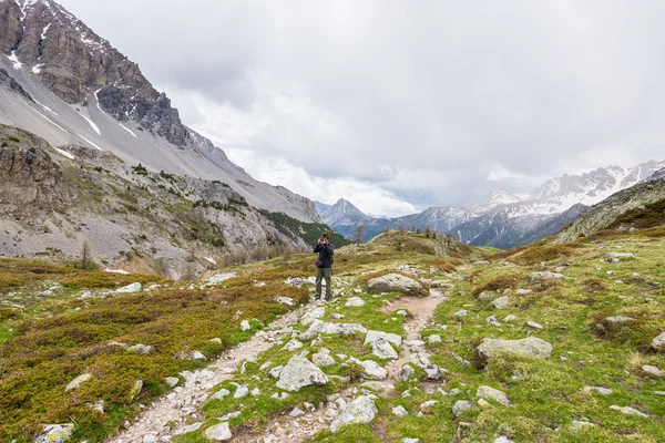 Hiker photographing landscape on the mountains with dramatic sky and storm clouds. Summer adventures and exploration on the Alps. — Stock Photo, Image