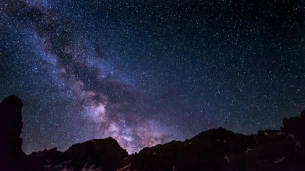 La aparente rotación de una Vía Láctea extraordinariamente brillante y el cielo estrellado más allá de la cordillera nevada, capturado a gran altitud en verano en los Alpes italianos. Tiempo de caducidad 4k video . — Vídeo de stock