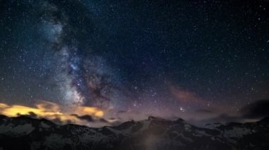 Olağanüstü parlak Samanyolu ve Karla kaplı dağ sırtı ötesinde yıldızlı gökyüzü, İtalyan Alpleri'nde yaz aylarında yüksek irtifada yakalanan görünür rotasyon. Time Lapse 4k video.