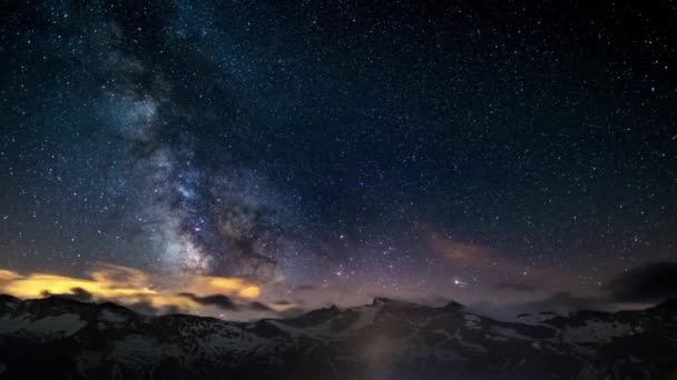 The apparent rotation of an outstandingly bright Milky Way and the starry sky beyond snowcapped mountain ridge, captured at high altitude in summertime on the Italian Alps. Time Lapse 4k video. — Stock Video