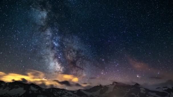 Очевидное вращение невероятно яркого Млечного Пути и звездного неба за заснеженным горным хребтом, захваченного на большой высоте летом в итальянских Альпах. Время для 4k-видео . — стоковое видео