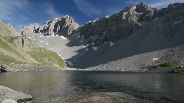 Hochalpensee in dramatischer Felslandschaft. Weitläufiger Blick auf den Berggipfel, der bei Sonnenuntergang glüht. — Stockvideo