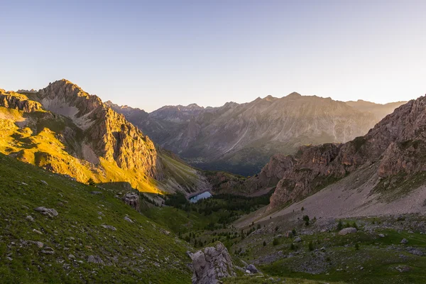 Pradera alpina y pastos colocados en medio de la cordillera de alta altitud al atardecer. Los Alpes italianos, destino turístico famoso en verano . —  Fotos de Stock