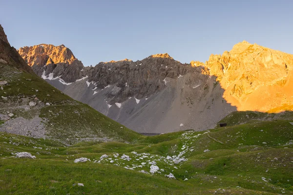 Prado alpino e pasto situado em meio a alta altitude gama de montanhas ao pôr do sol. Os Alpes italianos, famoso destino de viagem no verão . — Fotografia de Stock