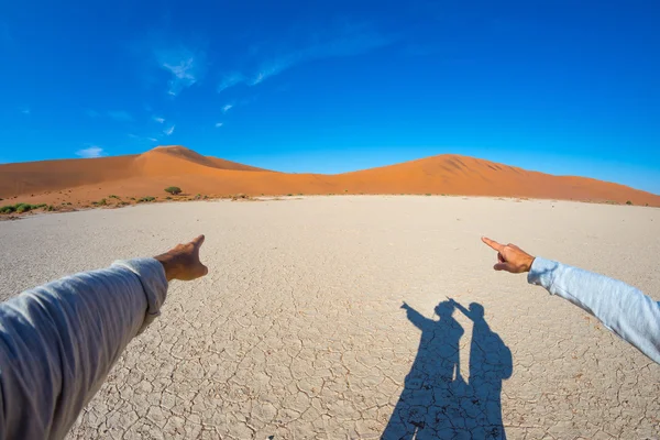Fingers pointing to the scenic sand dunes of Sossusvlei, Namib Naukluft National Park, Namibia, Africa. Adventure and exploration in Africa, concept of people traveling around the world.