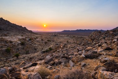 Namib Çölü, Aus, Namibya, Afrika renkli gün batımı. Ufuk, parlak kayalar ve canyon ön planda turuncu kırmızı Menekşe açık gökyüzü.
