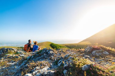 Erkek ve kadın, İtalya 'nın Umbria bölgesinde Monte Cucco, Appennino dağlarında yürüyüş yapıyor. Çift dağın tepesinde gün batımını seyrediyor. Yazın açık hava aktivitesi.