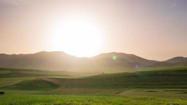 Zaman aşımı: İtalya 'nın Castelluccio di Norcia dağları üzerinde gün batımı. Köy, Apeninler 'deki ünlü renkli çiçek düzlükleri çiçek açan tarım tarlalarının tepesine tünemişti.