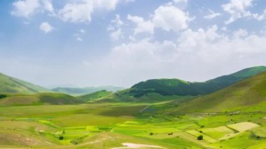 Zaman aşımı: İtalya 'nın Castelluccio di Norcia dağları üzerinde hareket eden bulutlar. Köy, Apeninler 'deki ünlü renkli çiçek düzlükleri çiçek açan tarım tarlalarının tepesine tünemişti.