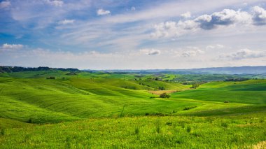 İtalya, Toskana, Volterra Vadisi 'ndeki eşsiz yeşil manzara. Ekilmiş tepe ve mısır gevreği tarlaları üzerinde manzara dramatik gökyüzü ve günbatımı ışığı. Toscana, İtalya.