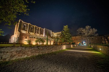 San Galgano, İtalya Manastırı - Mayıs 2021: Abbazia di San Galgano (orijinal adı), çökmüş çatılı antik bir katedralin kalıntısı, İtalya 'nın Toskana kentinde turizm merkezi. Geceleyin dış görünüş.