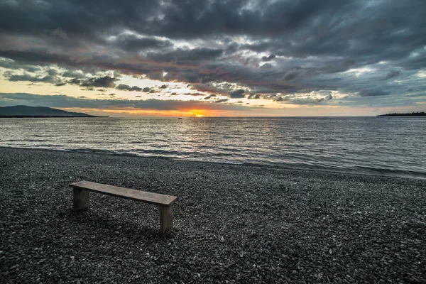 Leere Bank am Strand bei Sonnenuntergang — Stockfoto