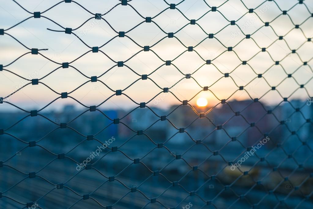 Blurred cityscape beyond metal fence