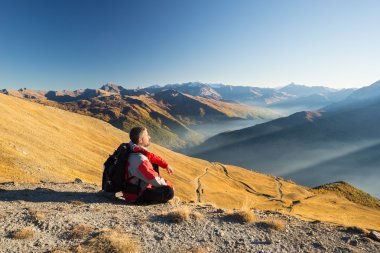 Hiker resting on the mountain top clipart