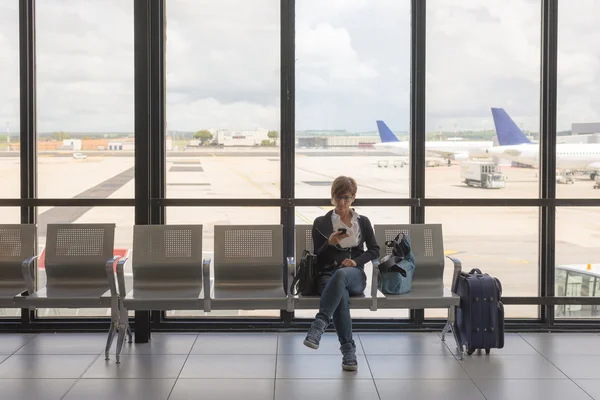 Esperando en la terminal del aeropuerto usando el teléfono —  Fotos de Stock