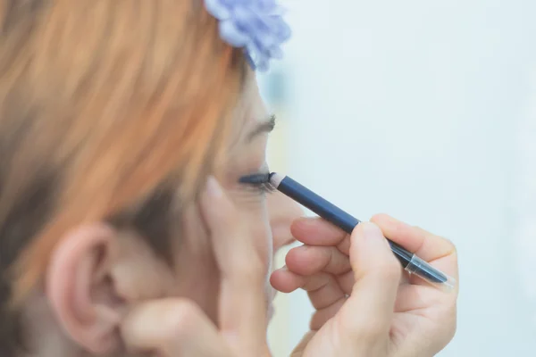 Lady applying blue eyeliner on eyelid — Stock Photo, Image