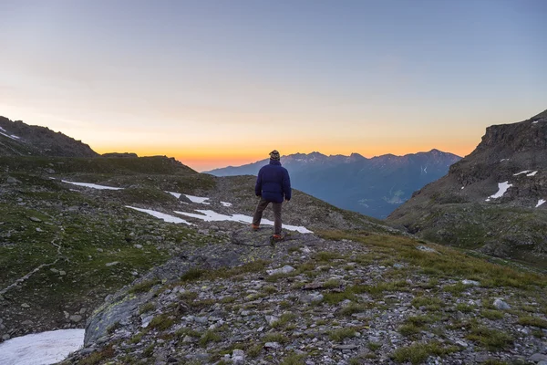 Uma pessoa a ver o nascer do sol no alto dos Alpes — Fotografia de Stock