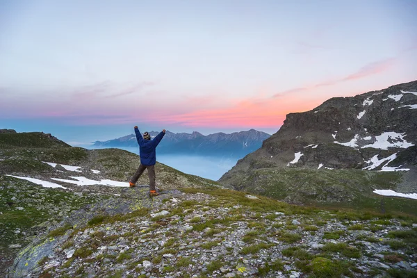 Uma pessoa a ver o nascer do sol no alto dos Alpes — Fotografia de Stock