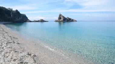 Palmi Calabria İtalya 'nın kayalık kıyıları turkuvaz şeffaf deniz dalgaları yumuşak kumlu plajlar ve parlak gökyüzünün altındaki uzak uçurumlar barışı ve Akdeniz güzelliğini simgeliyor..