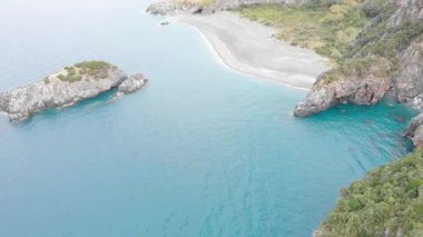 Calabria İtalya 'daki Arcomagno kıyılarının havadan görünüşü turkuaz deniz toplantılarının engebeli uçurumları ve yemyeşil Akdeniz bitki örtüsüyle çevrili gizli mağaraların dokunulmamış doğal güzelliği simgelediğini gösteriyor.