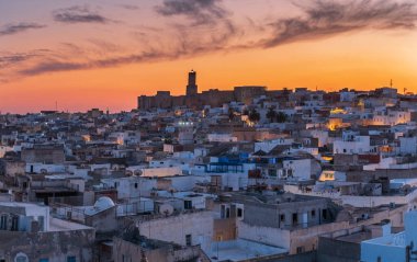 Sousse, Tunus 'un tarihi medine üzerinde gün batımı, yoğun kentsel çatılar ve sıcak akşam ışığı, kültür, gelenek, günlük şehir hayatı ve Kuzey Afrika atmosferini çağrıştırıyor.